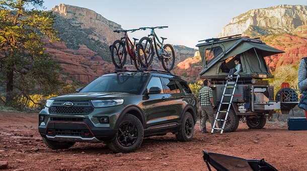 Un VUS Ford équipé d’un porte-vélo sur le toit et stationné sur un terrain de camping.