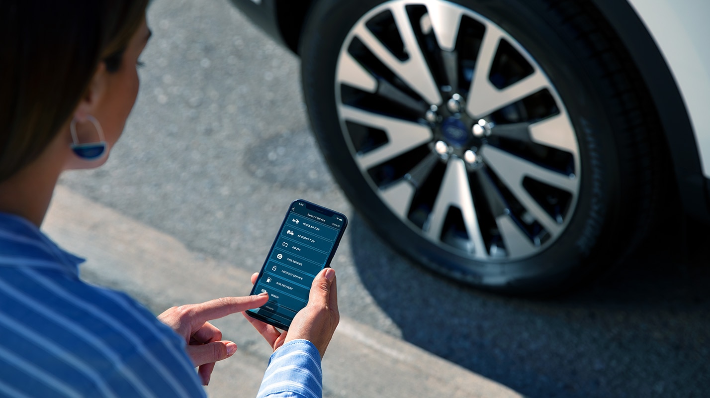 Woman holding phone looking at the Roadside Assistance app.