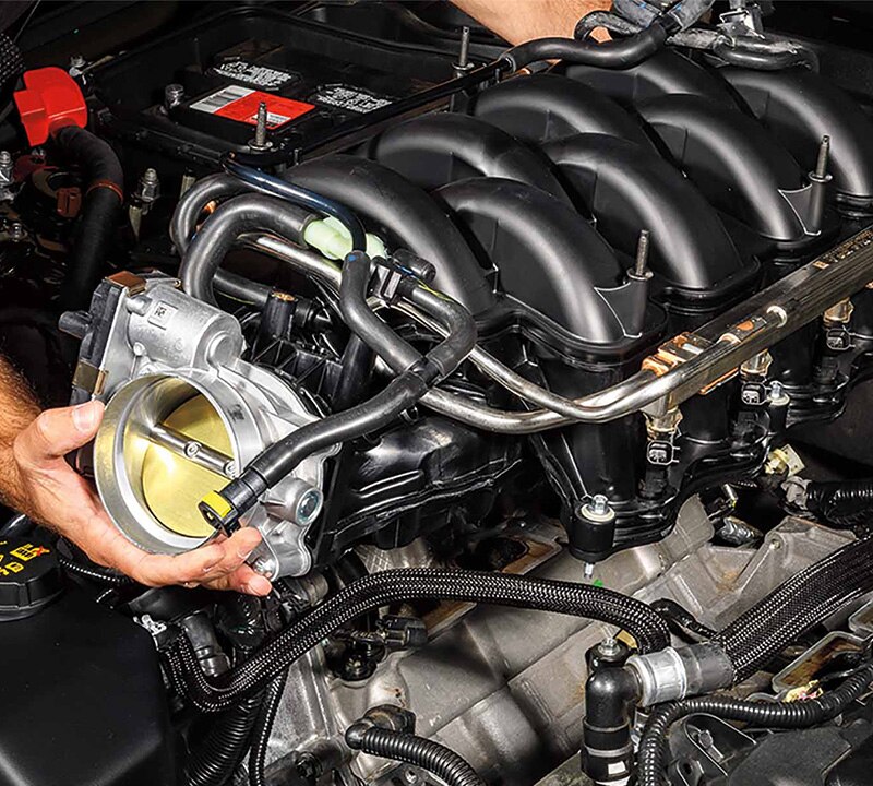 Ford Service Technician working on a vehicle engine.