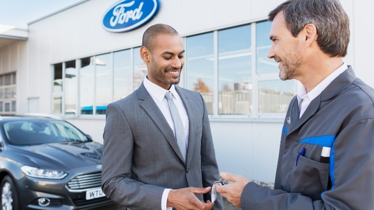 Twee mannen staan voor een Ford Agent gebouw