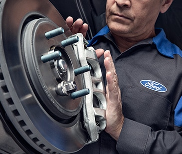 A Ford Service Technician holds an engine part.