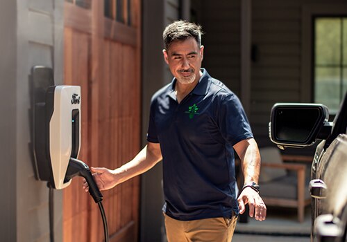 A man reaches for a Ford Connected Charge Station to plug into his Ford electric vehicle.