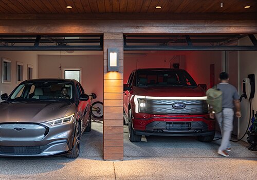A man walks into a garage next to a Ford F-150 Lightning® truck.