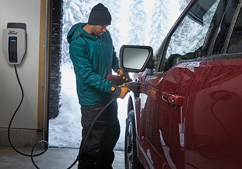 A man plugs a charger into a Ford F-150 Lightning® truck.