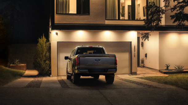 A 2024 Ford F-150 is parked in a driveway at night, illuminated by the home’s outdoor lighting.