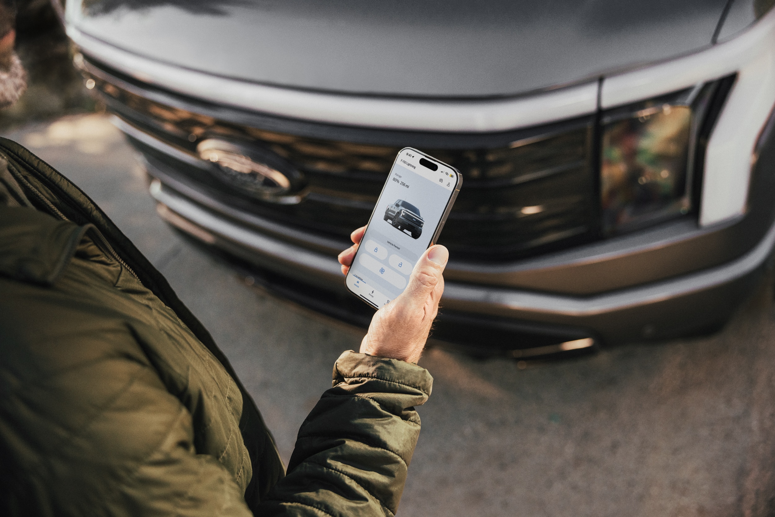 Close-up of a man looking at the FordPass App next to his Ford F-150 Lightning truck.