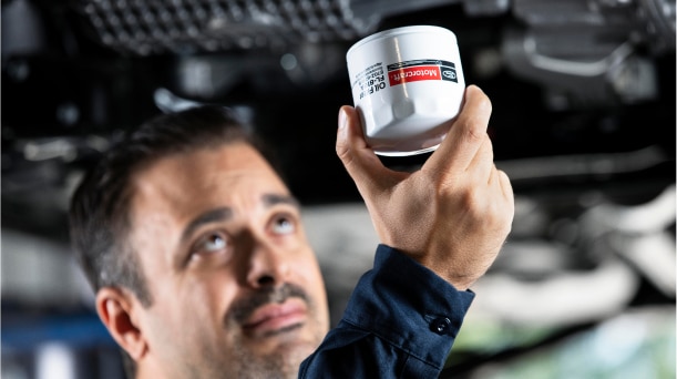 Technician installing an oil filter in a vehicle.