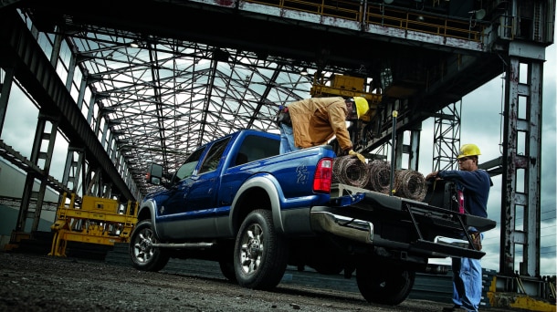 Two workers loading the bed of a Ford pickup.