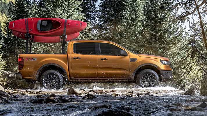 Ford Ranger driving over rocky terrain with two kayaks on a Kayak Rack.