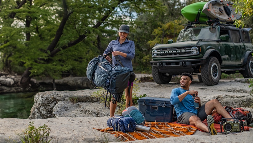 Couple with gear and Bronco by a river