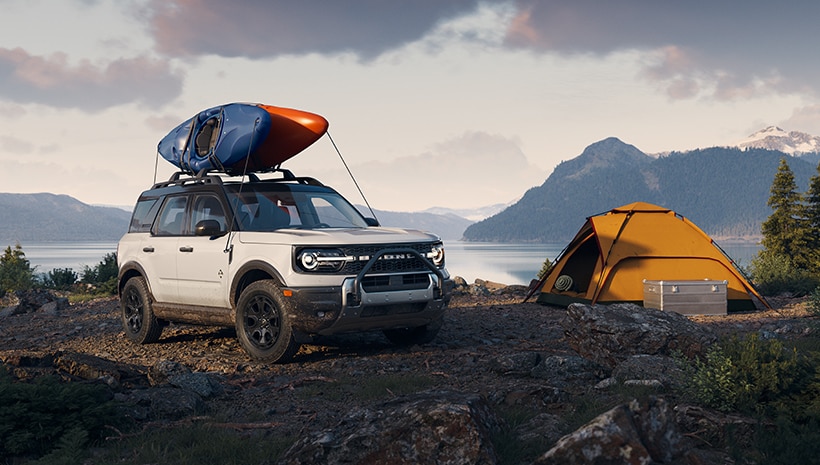 Vehicle parked by mountain lake and tent