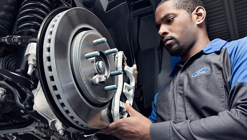 Ford® Service technician installing new brake pad on rotor