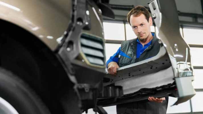 Un Técnico de Servicio Ford instala una nueva defensa delantera en un vehículo Ford.