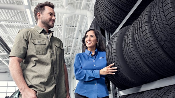 Ford service technician showing a customer a selection of tires on a rack