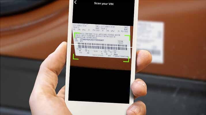 Una mano que sostiene un smartphone y escanea el código de barras del Número de Identificación del Vehículo.