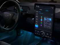 A dark image from the front passenger's perspective of a large, illuminated SYNC® screen and illuminated driver's side footwell.