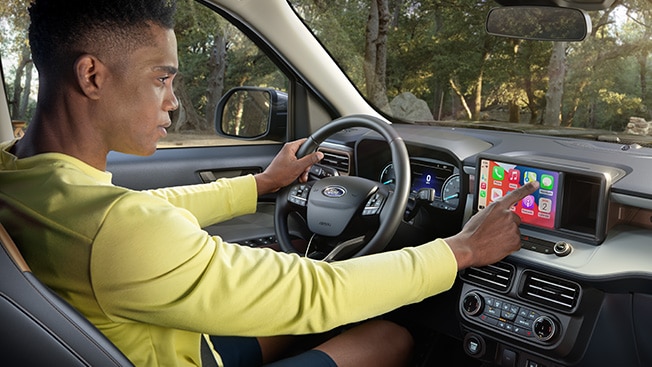 A driver glances at the in-vehicle SYNC3 touchscreen of a Ford vehicle while making a selection on Apple CarPlay.