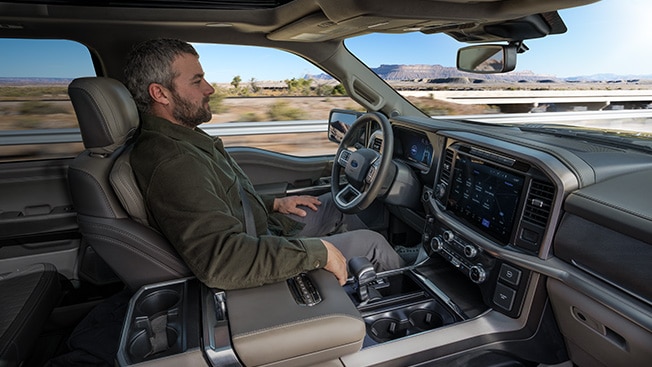 A Ford owner sits back and relaxes while using BlueCruise on a divided highway.
