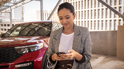 A person stands in front of a parked Ford Explorer looking at a smartphone.