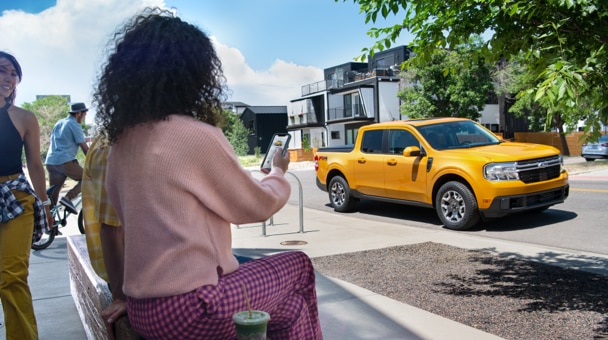ELIGE UNA FECHA Y HORA Transeúntes mirando y tomando fotos de una camioneta Ford en yellow estacionada en una calle soleada