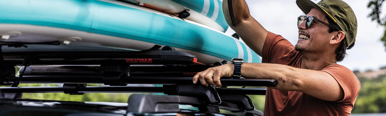 An owner straps down paddle boards to a roof rack on their Ford vehicle.