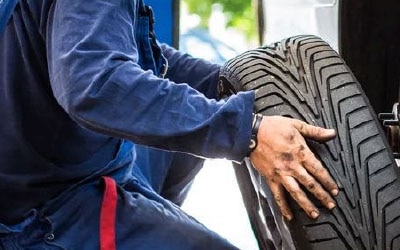 Un technicien de révision Ford installe un pneu sur un véhicule.