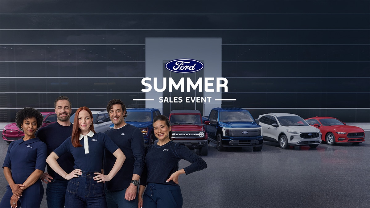 A Ford dealership with vehicles and the crew supporting the Ford For America Summer Sales Event.