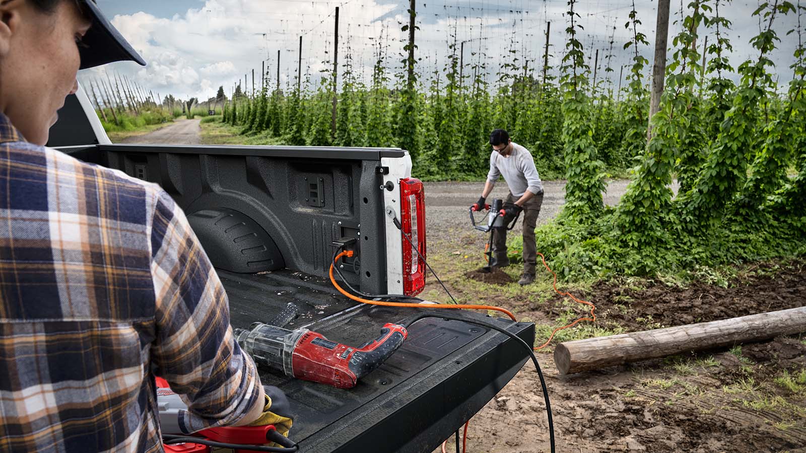 A couple of workers utilize the Pro Power onboard capabilities of the Super Duty® truck to power an auger in a field.
