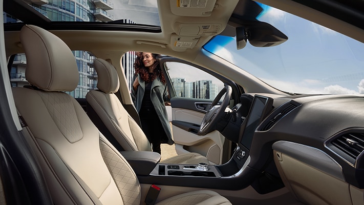 The interior of a 2023 Ford Edge® SUV with the driver's side door open and a driver standing nearby.