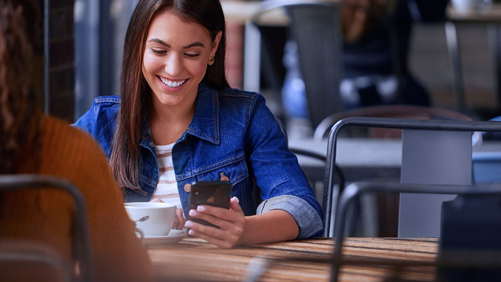 A woman is shown holding a smartphone in her hand.