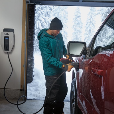 A man hooks a Ford F-150 Lightning truck up to a charger
