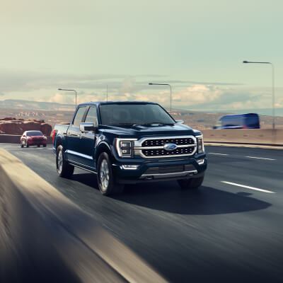 A blue 2023 Ford F-150® Platinum® truck being driven on a highway.