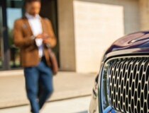 A person is shown approaching a Lincoln® vehicle while using their smartphone
