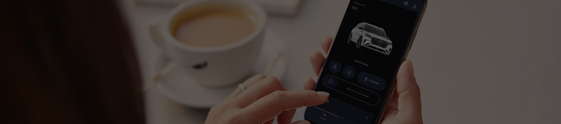 Una persona sostiene un teléfono inteligente y ve la aplicación Lincoln Way frente a una taza de café.
