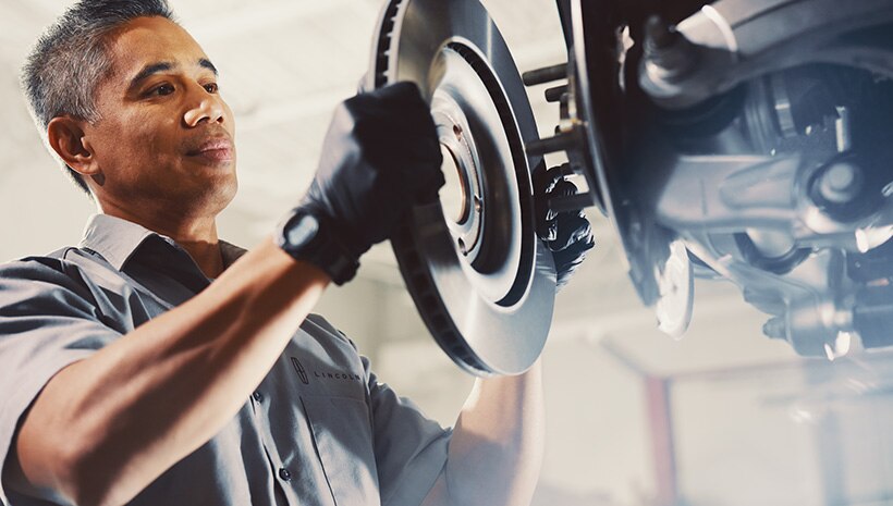 Lincoln technician fits a brake onto a Lincoln vehicle