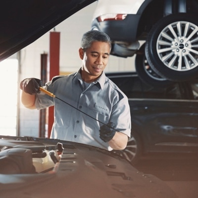 A Lincoln service technician checks the oil of a Lincoln vehicle