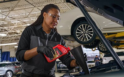 Service Technician pouring oil into a vehicle