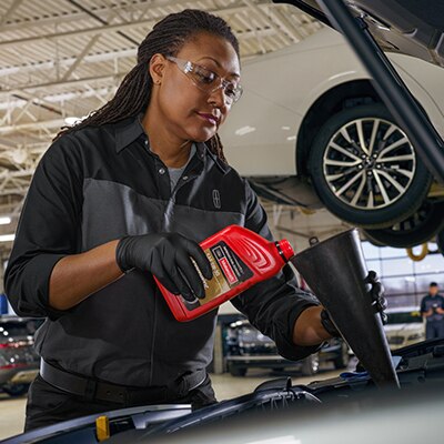 Service Technician pouring oil into a vehicle