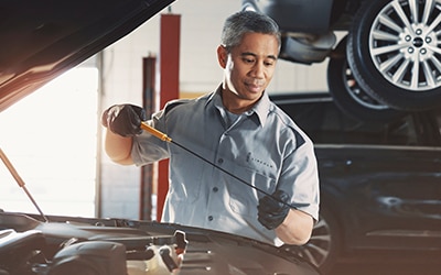 Service Technician pouring oil into a vehicle.