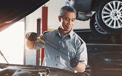 A Lincoln service tech is checking the oil on a vehicle.