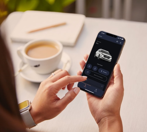 A hand is shown holding a smartphone displaying the Lincoln Way® App interface.