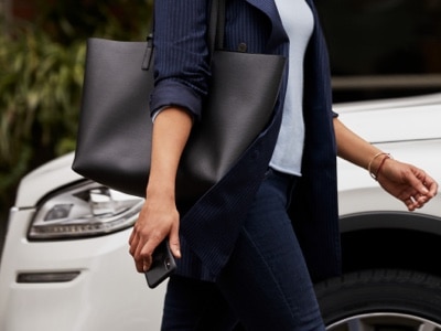A person approaches a Lincoln® vehicle while holding a smartphone