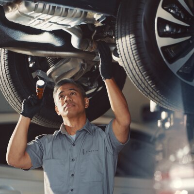 Un técnico está trabajando debajo de un vehículo Lincoln.
