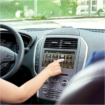 Se ve la mano de un conductor tocando la pantalla de SYNC® en un vehículo Lincoln