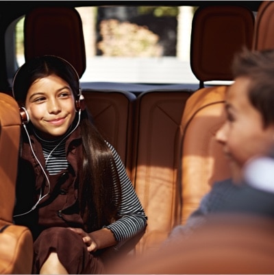 Una persona con los auriculares puestos está sentada en el asiento trasero de un vehículo Lincoln.