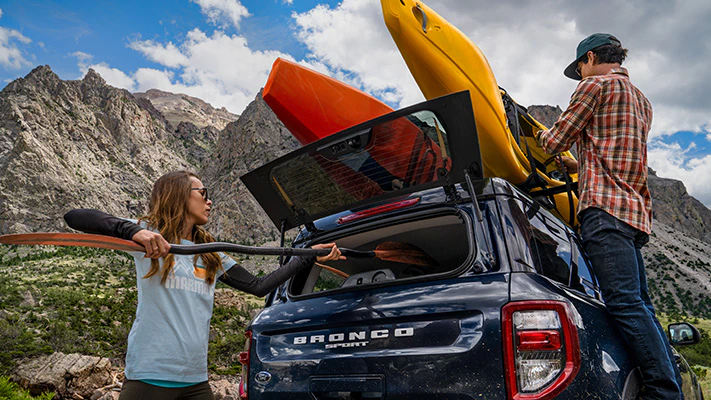A couple load up and tie down kayaks on their Bronco Sport® SUV after a day on the river.