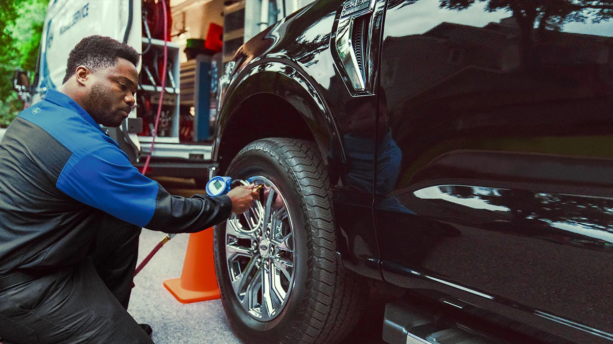 A Ford Mobile Service technician checks the tire pressure on an F-150® truck.