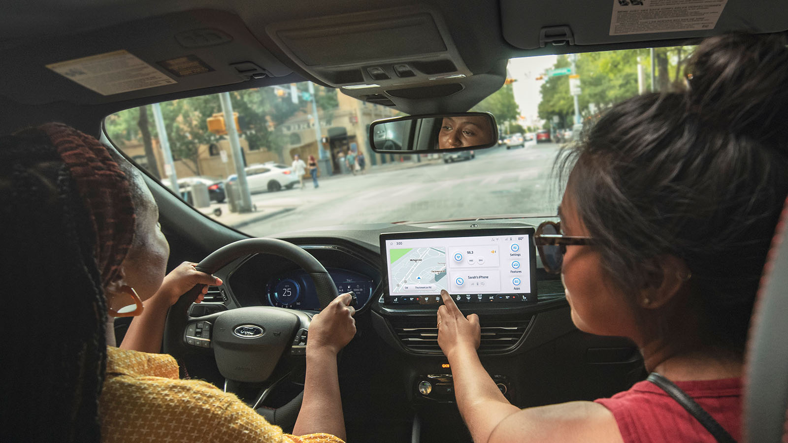 A driver and passenger use connected navigation while driving down a city street in their Escape® SUV