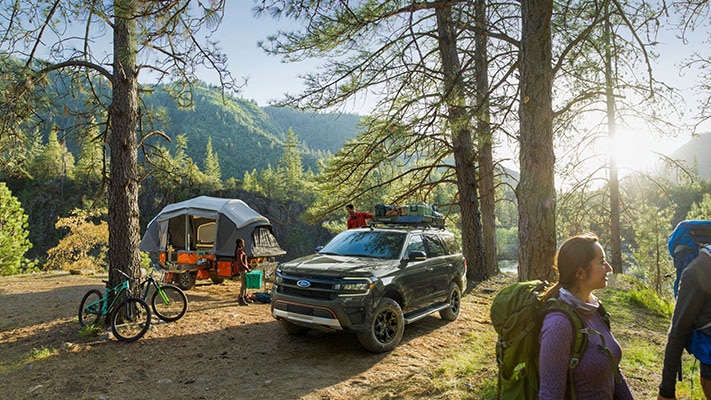 A couple unload camp gear from their Expedition® SUV at their campsite.