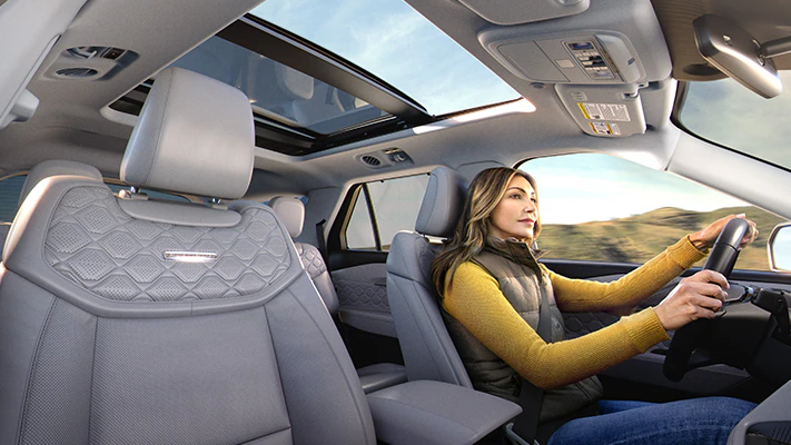 An owner drives their Explorer® SUV with the sunroof open. Late afternoon light floods through the passenger side windows.